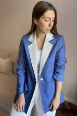 Blazer de lino color blanco con solapas y cuello en color beige, corte entallado, botón de nácar, tajo en la espalda y bolsillos laterales.