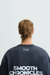 Sudadera relaxed fit confeccionada en tejido de algodón con el interior rizo. Cuello redondo y manga corta. Estampación de gráficos y textos combinados a contraste en delantero y espalda.