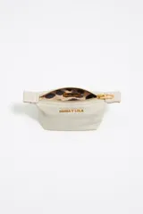 Monedero trapecio de tamaño mini, color crudo, con cierre dorado y logo de la marca estampado en dorado.