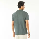 Chomba verde de punto gofrado con cuello polo y tapeta con botones.