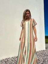 Vestido largo de tejido de punto con rayas verticales multicolores y abertura frontal.