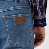 Pantalón de jean Wrangler corte slim, color azul medio, con bolsillos delanteros y traseros.