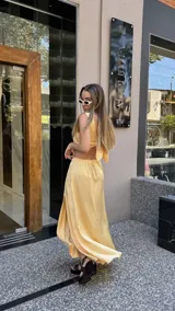 Vestido largo color durazno con escote pronunciado en V y aberturas laterales en la cintura. Presenta un drapeado frontal y falda con tajo lateral.