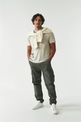 Pantalón cargo verde militar sin puños, de corte recto, con bolsillos laterales y traseros. Se ajusta a la cintura con cinturón de cuero marrón.