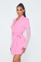 Vestido corto tipo blazer color rosa, con escote cruzado, cinturón y mangas largas de strass.