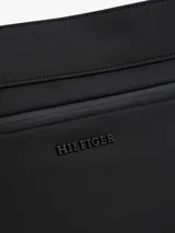 Cartera mensajera negra de poliuretano con correa de tela ajustable con el logo de la marca. Tiene cierre de cremallera, bolsillo interior y exterior con cremallera, y logo metálico en la parte delantera.