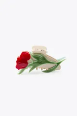 Pinza para el pelo color crema con forma de flor roja y hojas verdes en relieve.