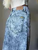 Pantalón jean cargo de pierna ancha y tiro alto, con proceso de lavado artesanal que hace que cada prenda sea única. Presenta bolsillos laterales con solapa y botón.