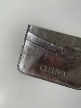 Tarjetero dorado de cuero vacuno con cuatro divisiones para tarjetas y un bolsillo central.