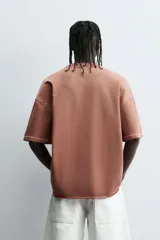 Camiseta color beige de corte holgado, cuello redondo y manga corta.