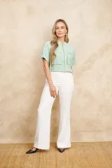 Chaqueta bomber color verde agua, con cierre frontal dorado, bolsillos grandes con cierre y mangas cortas con ajuste mediante lazos.