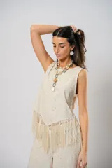 Blusa beige de lino bordado, sin mangas y con terminación en flecos.