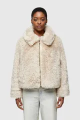 Chaqueta corta color beige de piel sintética con cuello amplio y cierre frontal con cremallera.
