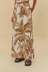 Pantalón ancho con estampado de hojas de palmera en tonos marrón y beige. Tiene cintura alta con cierre discreto y bolsillos laterales.