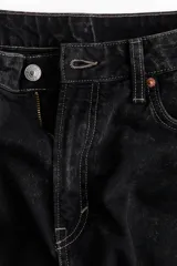 Pantalón de jean negro con efecto lavado, tiro alto, corte holgado en cintura y cadera, estilo baggy de muslo a bajo, cinco bolsillos y cierre con botón.