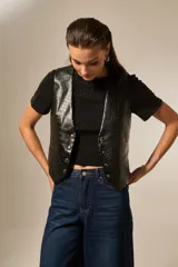 Chaleco negro de eco-cuero con textura de cocodrilo, corte entallado y cierre frontal con botones metálicos.