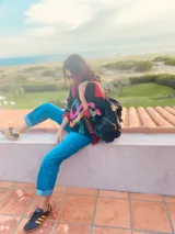 Sweater negro con detalles bordados de colores en el frente y mangas largas. Tiene cuello redondo y puños y ruedo acanalados. El cuerpo es de color rojo y las mangas son negras.