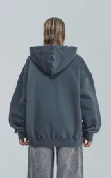 Hoodie gris oscuro con cierre amarillo parcial en el cuello y bolsillo tipo canguro.