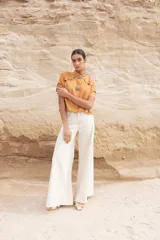 Blusa color camel con cuello mao, cierre frontal con botones y aberturas geométricas en hombros, mangas y cintura.