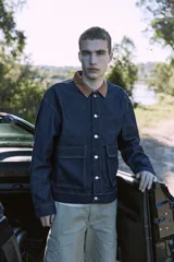 Campera de denim azul oscuro con cuello clásico marrón, cierre frontal con botones metálicos, bolsillos delanteros con solapa y puños con botones. Confeccionada en tejido denim resistente con estructura de sarga.