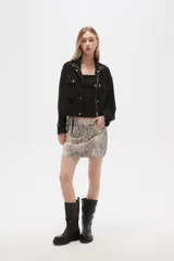 Campera color beige de manga larga, con cuello alto, cierre frontal con cremallera y botones a presión, bolsillos con solapa en el pecho y puños con trabilla ajustable.