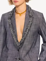 Blazer confeccionado en lino con apariencia denim, con solapa y cuello con flecos. Cierre con botones plateados y forro de tafeta jacquard.