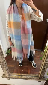 Bufandón de gran tamaño con diseño a cuadros en múltiples colores, suave al tacto y con flecos en los extremos.