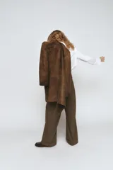 Abrigo largo de piel 100%, color marrón con efecto desgastado o envejecido. Presenta cuello solapa de muescas, manga larga, cierre frontal de botones y bolsillos de plastrón delanteros.