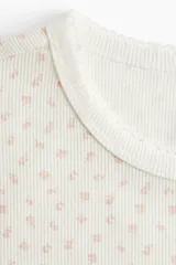 Remera blanca con estampado floral, de corte ajustado en punto suave, con ribete fino en el cuello y acabado sobrehilado en mangas y bajo.
