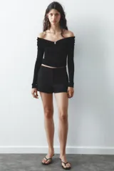 Shorts tiro bajo color negro con bolsillos delanteros. Cierre frontal con cremallera y ganchos metálicos.