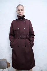 Trench color borgoña con doble botonadura, cuello solapa, cinturón con hebilla y trabillas en los hombros.
