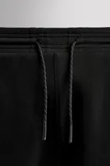 Pantalón jogger color marrón oscuro, corte regular fit, confeccionado en tejido técnico compacto de algodón con elasticidad. Cuenta con cintura elástica ajustable con cordón, bolsillos frontales y bolsillo lateral con cierre de cremallera.