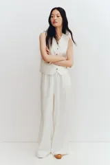 Pantalón culotte color blanco hueso, de tiro alto con cintura elástica, corte amplio y bolsillos laterales.