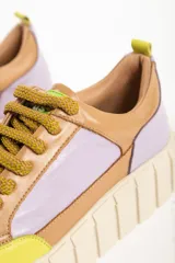 Zapatillas deportivas de cuero color beige con detalles en lila y amarillo.