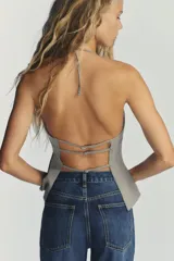 Top color gris con raya diplomática, de cuello halter ajustable y escote redondo. Espalda descubierta con tiras ajustables, forro interior y cierre lateral con cremallera oculta.