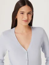 Saco celeste de tejido de punto con cuello en V y cierre frontal con botones.