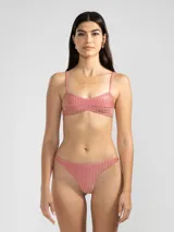Conjunto de bikini color rosado con textura acanalada. El corpiño es de corte triangular con tirantes finos y la bombacha es tipo colaless.