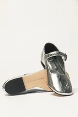 Zapato estilo Mary Jane color marrón, de cuero, con punta redondeada y tira sobre el empeine con hebilla.