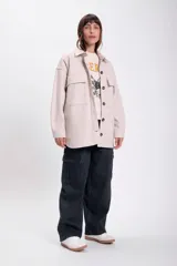 Sobrecamisa beige de paño con cuello clásico, cierre frontal con botones a tono, dos bolsillos de parche en el pecho y corte holgado.