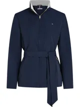 Campera Tommy Hilfiger azul marino con cuello alto blanco, cierre frontal con cremallera, mangas largas y cinturón ancho de tela del mismo tejido para ajustar en la cintura.