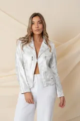Chaqueta plateada de cuero ecológico laminado, con cuello solapa, cierre cruzado con broche y detalles de cierres y tachas.