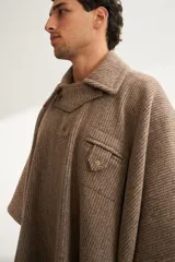 Poncho unisex de lana fina color marrón claro, con cuello polo, cartera con broches a presión y bolsillo ojal.