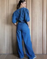 Conjunto de camisa y pantalón de lino blanco. La camisa es de manga larga y se ata en la parte delantera. El pantalón es de corte ancho y tiene cordón en la cintura.