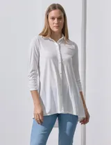 Camisola blanca de manga tres cuartos, marca Rio & Rian. Cuello con solapa y abertura central con botones. Manga con detalle fruncido.
