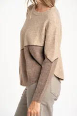 Sweater de tejido de punto con diseño de bloques de color en tonos beige, blanco roto y bordó. Presenta cuello redondo y mangas largas.