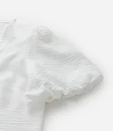 Blusa blanca de crepé con escote en V, abotonada en el frente y mangas cortas abullonadas.