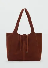 Bolso tipo shopper de gamuza color marrón, con doble asa corta y asa larga para el hombro. Tiene cierre de lazo y forro interior de algodón con un bolsillo con cremallera.