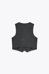 Chaleco corto con estampado pata de gallo en tonos grises, escote en pico, sin mangas, bolsillos simulados y cierre frontal con botones.
