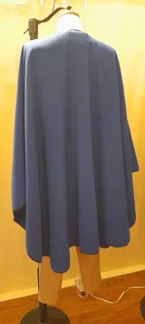 Ruana larga azul royal de paño con presilla y vivo negro en el borde.