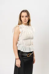 Top blanco con textura arrugada, cuello redondo, sin mangas y volados en los hombros.